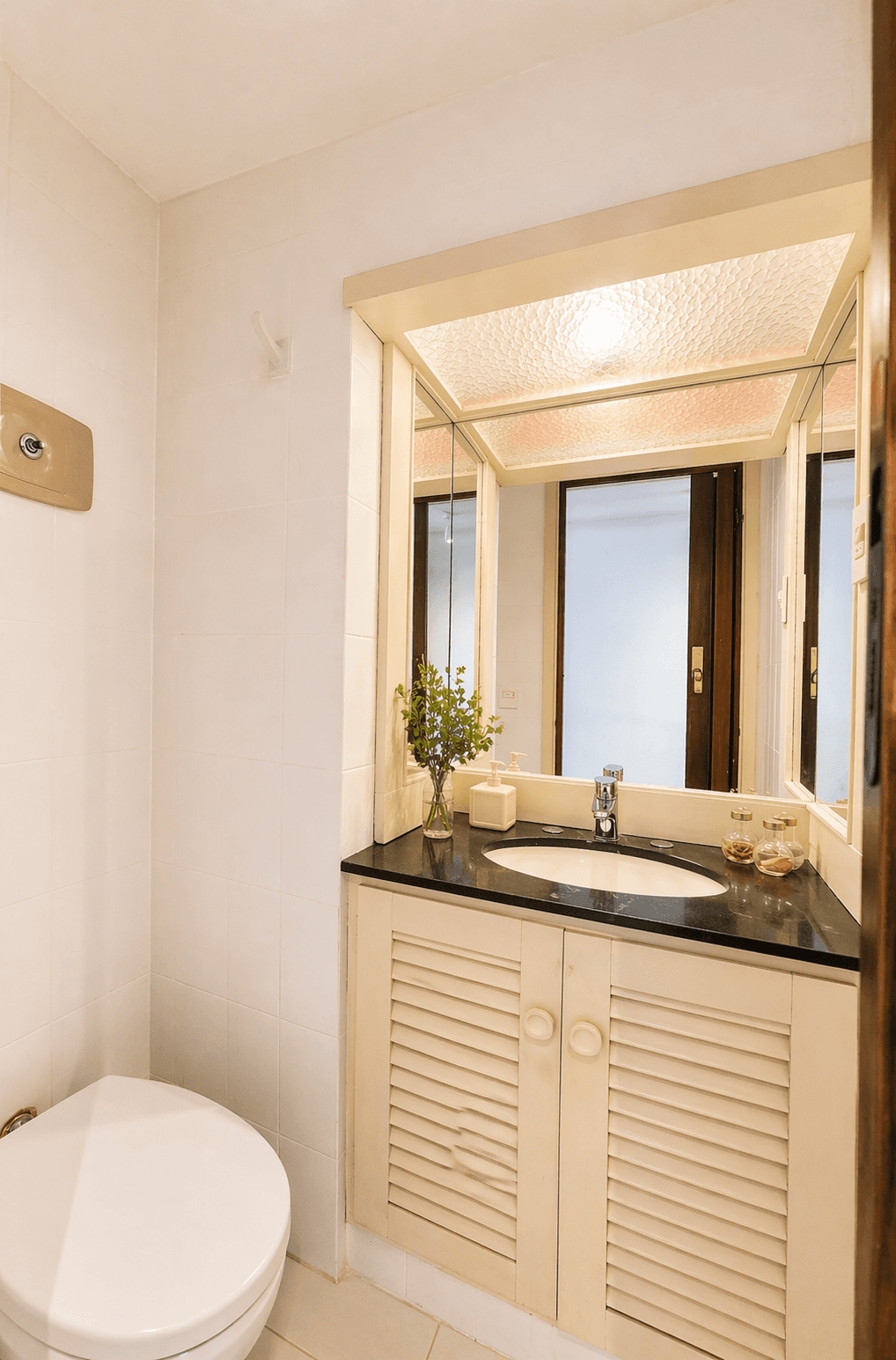 Baño auxiliar con lavabo, amplia mesada, espejo e inodoro. Cuenta con mueble bajo mesada para guardado, revestimientos claros e iluminación superior.