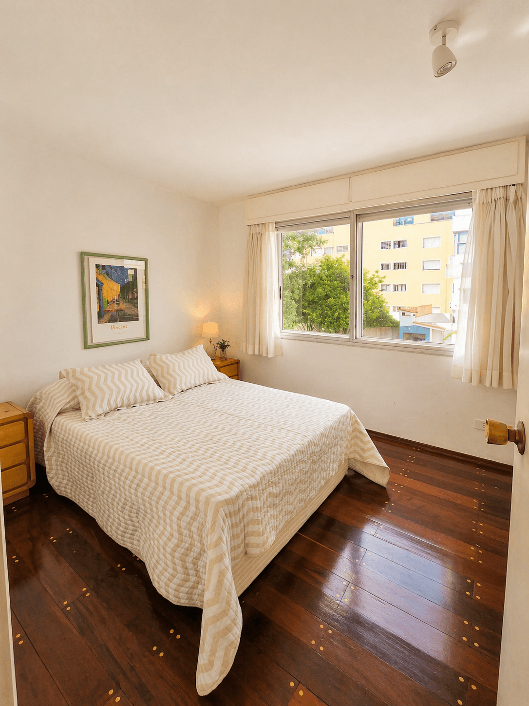 Dormitorio luminoso con cama doble, gran ventanal con vista exterior y pisos de madera. Cuenta con mesas de luz y buena entrada de luz natural.